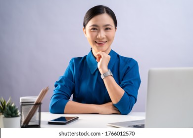 Asian Woman Happy Smiling In Blue Shirt Looking At Camera, Working On A Laptop At Office. Isolated On White Background.