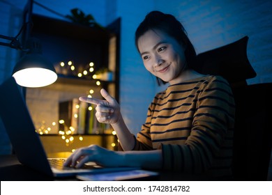 Asian Woman Happy Smiling Working On A Laptop At The Night At Home. WFH. Work From Home Avoid COVID 19 Concept.