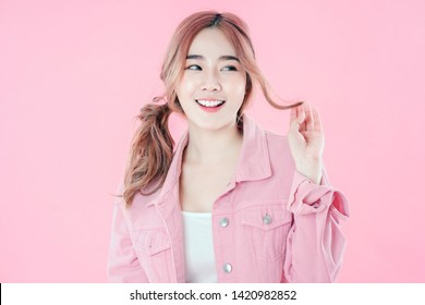 Asian woman happy with special deals & discounts of promotions, Pink jean clothing ponytail hairstyle, pink background
