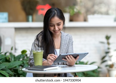 Asian Woman Are Happy To Use A Tablet At A Coffee Shop.