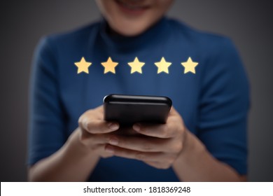 Asian woman happy using smart phone for check feedback, reviews with five stars icon hologram effect. Isolated on background.