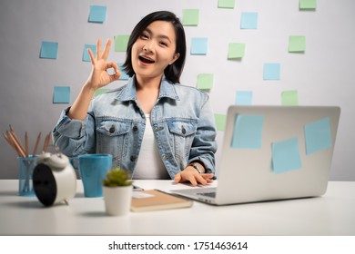 Asian Woman Happy Working On A Laptop Showing OK Sign At Home Office. WFH. Work From Home. Prevention Coronavirus COVID-19 Concept.