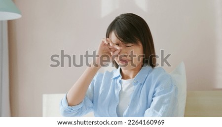 asian woman has allergy and she is rubbing her eyes on bed in bedroom