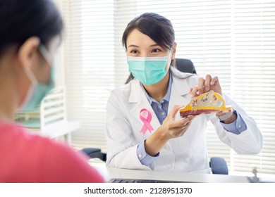 Asian Woman Has Breast Cancer Diagnosis In Hospital - Female Doctor Explaining By Anatomical Model While They Wear Protective Face Mask To Prevent COVID19