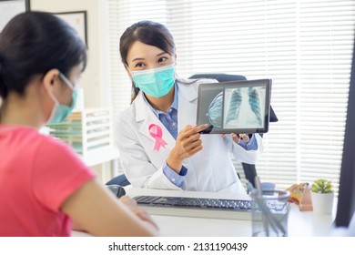 Asian Woman Has Breast Cancer Diagnosis In Hospital - Female Doctor Showing Mammography Test Results And Xray To Patient On Digital Tablet While They Wear Protective Face Mask To Prevent COVID19