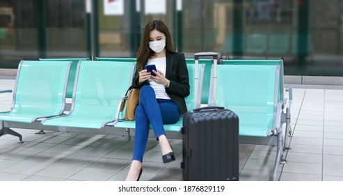 Asian Woman Has Business Trip And Use A Smartphone With Surgical Mask Face Protection While Waiting For The Metro Or Train In Station