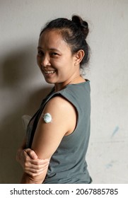 An Asian Woman Has A Cotton Swab On Her Arm After Getting Vaccinated.