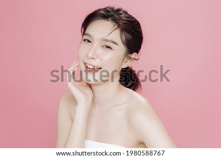 Asian woman has a lovely face is feeling happy with her perfect skin touch her face. She wears a white strapless bra. isolated over pink background. Skincare, cosmetology and plastic surgery concept.