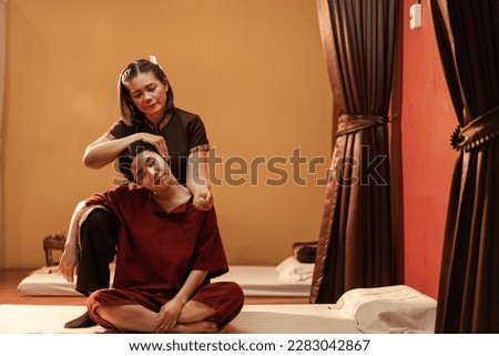 Asian woman has Thai massage with masseuse, Body massage of neck stretching for treat painful from office syndrome. Thai massage body with masseur.