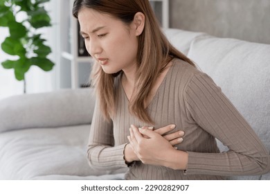 asian woman have chest pain caused by heart disease, leak, dilatation, enlarged coronary heart, press on the chest with a painful expression - Shutterstock ID 2290282907