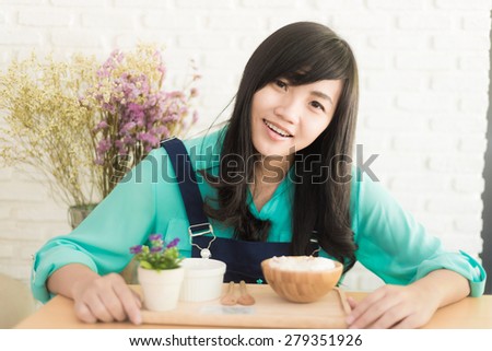 Asian woman having cup of coffee and icecream cake in cafe with white brick wall background