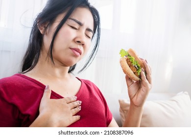 Asian Woman Having Heartburn, Acid Reflux After Eating Burger, Eating Junk Food Concept 