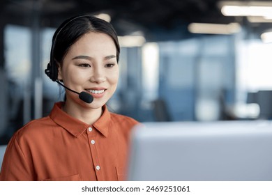 Asian woman with headset phone smiling working inside office with laptop, online customer support worker, businesswoman typing on keyboard, solving and helping customers remotely, successful woman. - Powered by Shutterstock