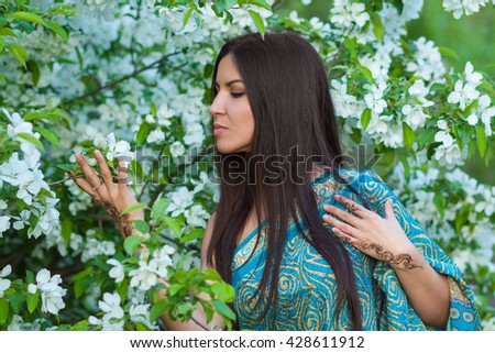 Asian woman with henna tattoo in flowering bushes