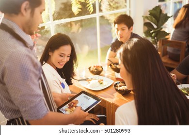 Asian Woman And Her Friends Were Ordering From The Menu, The Waiter At The Restaurant The Morning.