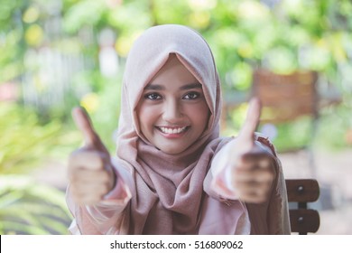 asian woman with hijab showing thumb up to camera