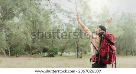 Asian woman hiking in the forest, feeling refreshed and energized.