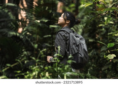 Asian woman is hiking with trekking poles in the forest. 