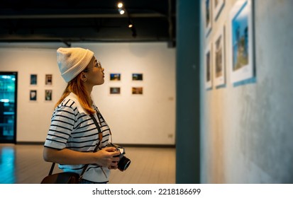 Asian woman hold camera at art gallery collection in front framed paintings pictures on wall and looking, Photographer visit at photo frame to leaning against at show exhibit artwork gallery picture - Shutterstock ID 2218186699