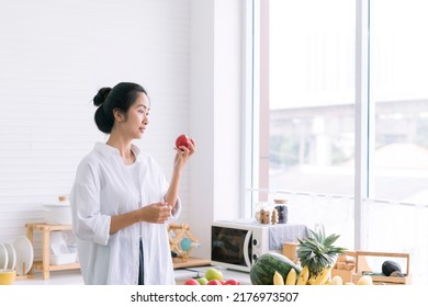 Asian Woman Holding Apples In The Kitchen. Shocked Woman With Apple On Her Hand.