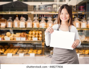 Asian Woman Holding Blank Paper With Bakery Shop Background