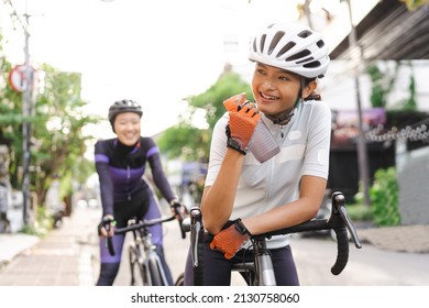 asian woman holding a bottle of water while sitting on her bike
