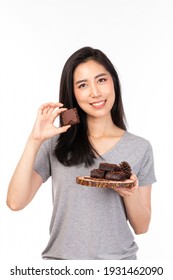 Asian Woman Holding Brownie Cake On Wooden Plate, Feeling Happy And Good Lifestyle Isolated On White Background. Beautiful Smiling Girl Holding And Eating Chocolate Isolated On White Background.