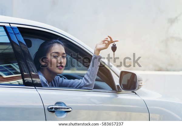Asian woman holding\
a car key, woman in car