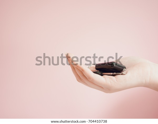 asian woman holding car key by beauty right\
hand with pink pastel\
background