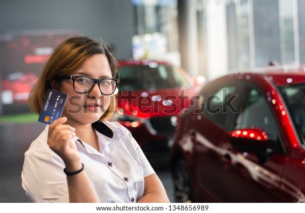 Asian woman holding credit card for car\
blurred bokeh background \
e-shopping marketing digital, consumer\
purchase shopping internet \
online\
image
