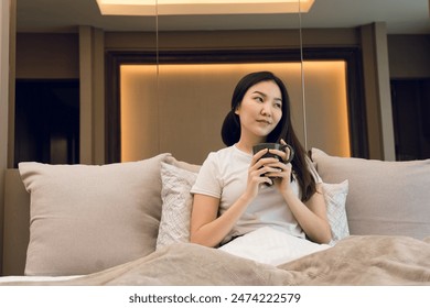 Asian woman holding a cup of coffee in the morning after waking up. - Powered by Shutterstock