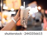 Asian woman holding the famous taiwanese bubble milk tea at night marketplace