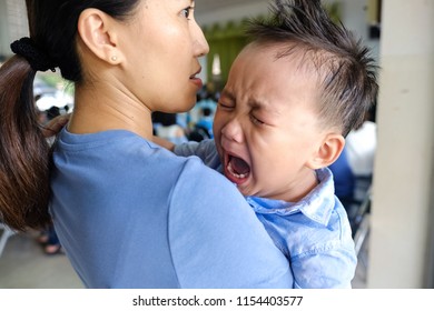 Asian Woman Holding Little Child Crying And Screaming With Tearful On Cheek