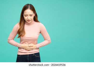 Asian Woman Holding On To Her Stomach Isolated On Green Background, Pain And Colic During Menstruation