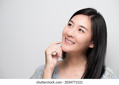 Asian woman holding orthodontic retainers.Teeth retaining tools after braces . - Shutterstock ID 2034771521