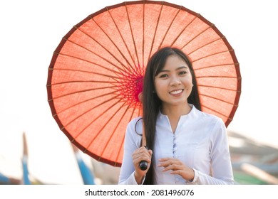 An Asian woman holding a red umbrella with a gondola. Girl with a red umbrella on wooden boat at bridge in Asia.U-bein bridge, Mandalay, Myanmar. - Shutterstock ID 2081496076