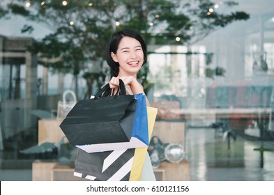 Asian Woman Holding Shopping Bag In Her Hand .