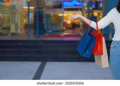 Asian Woman Holding Shopping Bags While Standing In Front Of A Shopping Mall, Shopping And Selling Concept. People. Payment.