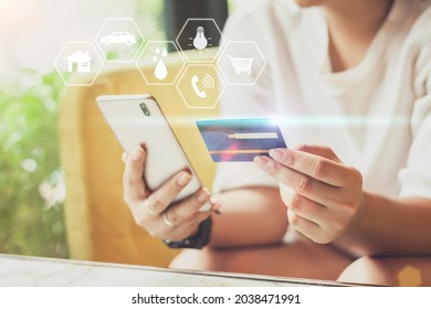 
Asian woman holding showing plastic credit card while holding a mobile phone with various icon concept payment pay for house, car, water, electricity, telephone bills, online shopping concept.