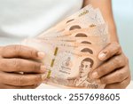 Asian woman holding Thai banknotes money, economy finance exchange trade investment.