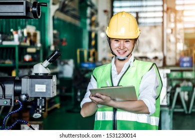 Asian Woman Is Industrial Engineer Or Qc Team Holding Th Clipboard While Standing In The Heavy Duty Manufacturing Shop Floor. Factory Worker Concept.