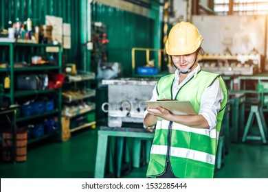 Asian Woman Is Industrial Engineer Or Qc Team Holding Th Clipboard While Standing In The Heavy Duty Manufacturing Shop Floor. Factory Worker Concept.