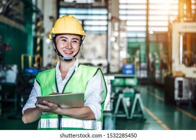 Asian Woman Is Industrial Engineer Or Qc Team Holding Th Clipboard While Standing In The Heavy Duty Manufacturing Shop Floor. Factory Worker Concept.