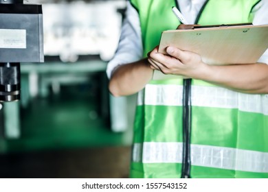 Asian Woman Is Industrial Engineer Or Qc Team Holding Th Clipboard While Standing In The Heavy Duty Manufacturing Shop Floor. Factory Worker Concept.