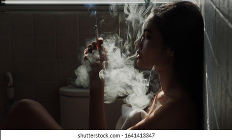 Asian Woman Inhaling And Cigarette Vaping. Female Secretly Smoking In Bathroom At Home. Concept Of Quit Smoking And Anti Cigarette.