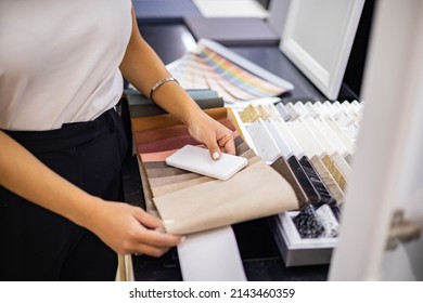 Asian woman interior designer chooses color of stone countertop for kitchen or facades compare with textile samples. Female professional indoor decorator working at showroom or residential apartment - Shutterstock ID 2143460359