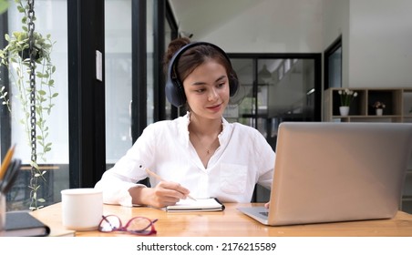 Asian Woman Interpreter Write Translation From Foreign Language To English Listen To Audio Record In Headset. 
