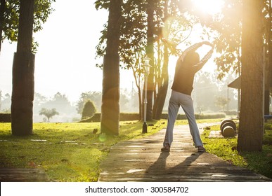 Asian woman jogging in park with cloudy sky and lens flare - Powered by Shutterstock