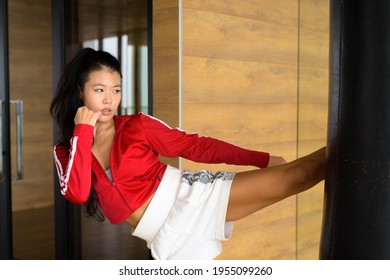 Asian Woman Kick Boxer Kicking Exercise Bag In Gym