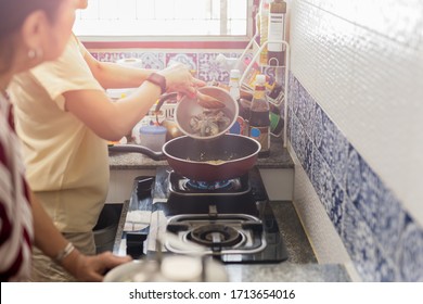 Asian Woman In The Kitchen Cooking Food With Her Mum During Covid-19 Quarantine.